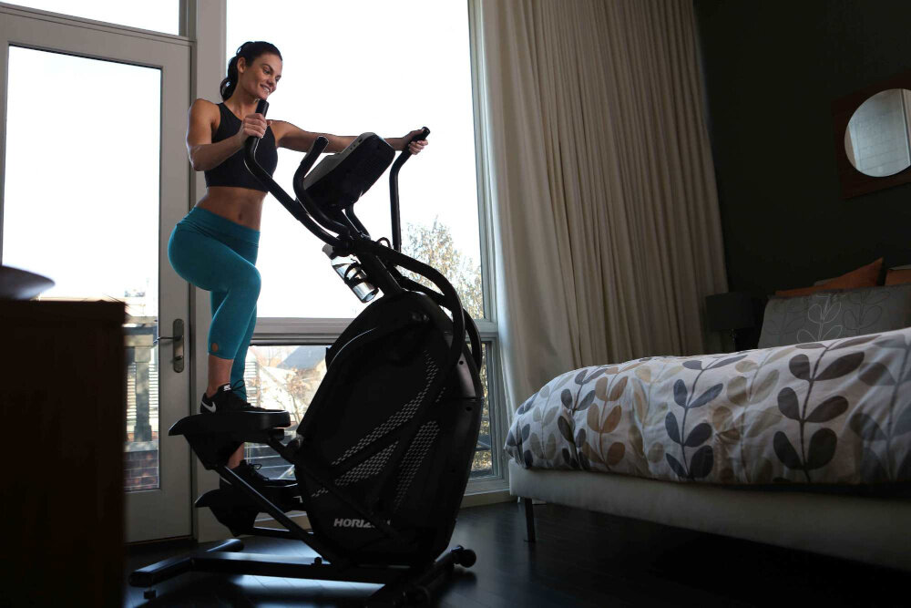 Orbitrek HORIZON FITNESS HT 5.0 Peak Trainer osoba ćwiczy na maszynie w pomieszczeniu intensywny trening w domu dbanie o zdrowie trening cardio angażowanie całego ciała