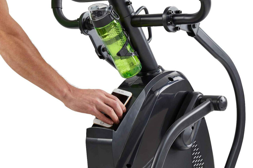 Orbitrek HORIZON FITNESS HT 5.0 Peak Trainer osoba odkłada telefon na półczeke bidon na uchwycie uchwyt na bidon półeczka na telefon