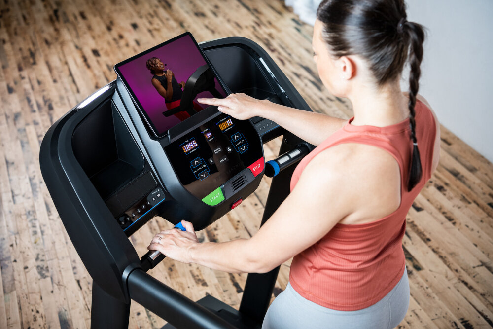 Bieżnia elektryczna HORIZON FITNESS T101 -27 1840W 18km-h pomieszczenie pokój osoba trzyma palec na ekranie trzyokienny wyświetlacz LED z podświetlanym ekranem LCD pełna kontrola nad parametrami ćwiczeń dane w czasie rzeczywistym można monitorować postępy przejrzysty wyświetlacz