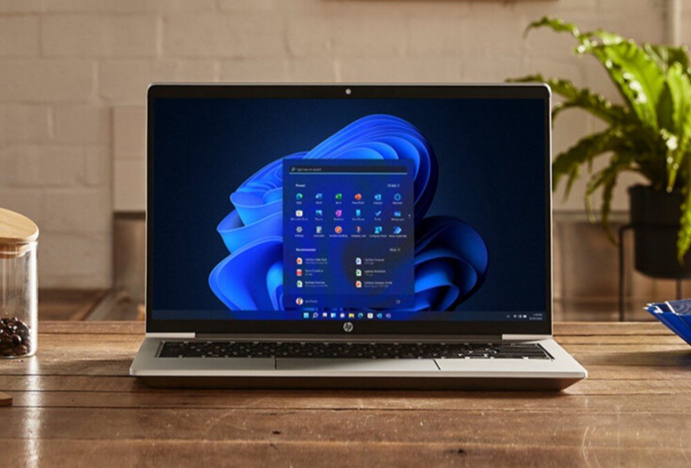 Laptop HP ProBook 440 G10 Laptop ustawiony na drewnianym stole z włączonym systemem operacyjnym, w tle roślina i kubek, ekran, rozdzielczość, jasność