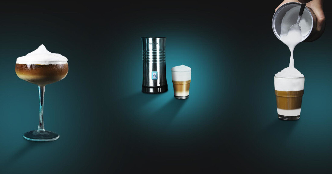 Na obrazie widoczny jest metalowy spieniacz do mleka oraz dwa napoje z pianką. Po prawej stronie ręka nalewa spienione mleko do szklanki z kawą.