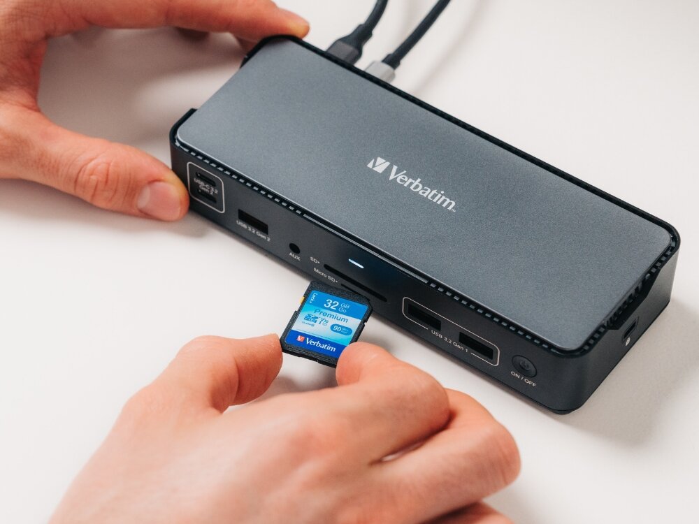 Na obrazie widoczna jest stacja dokująca z logo Verbatim, do której wkładana jest karta SD o pojemności 32 GB. Stacja posiada kilka portów USB i inne złącza.