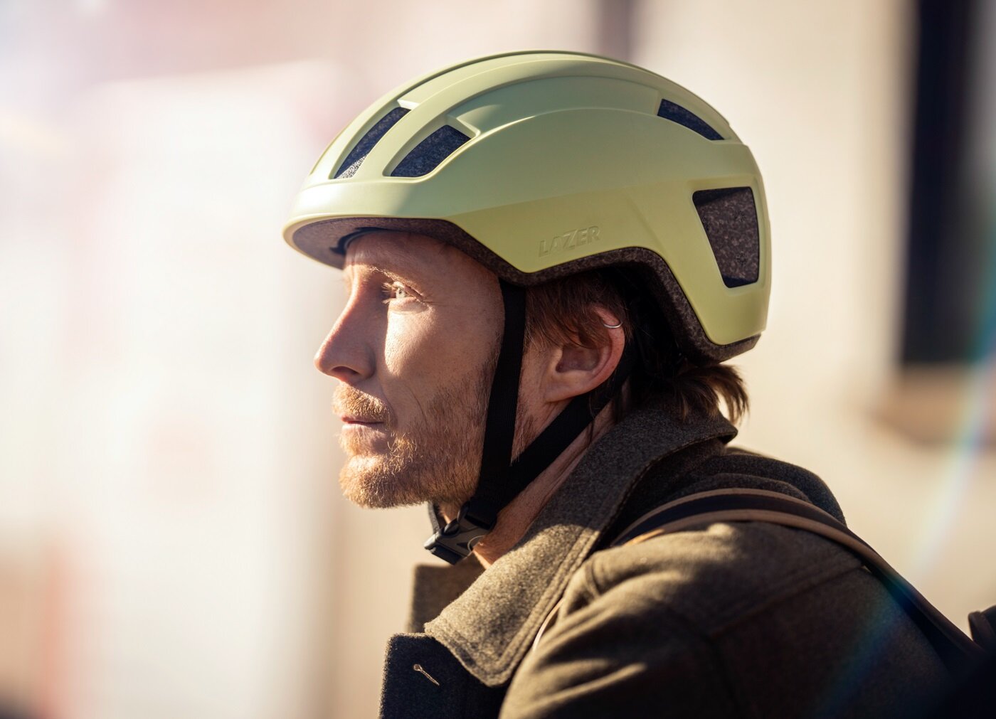 Kask rowerowy LAZER Verde KinetiCore zielony mat Miejski (rozmiar M/L) oosba w kasku na zblizeniu widok na kas z boku kask rowerowy z recyklingu płyty CD projektowanie cyrkularne
