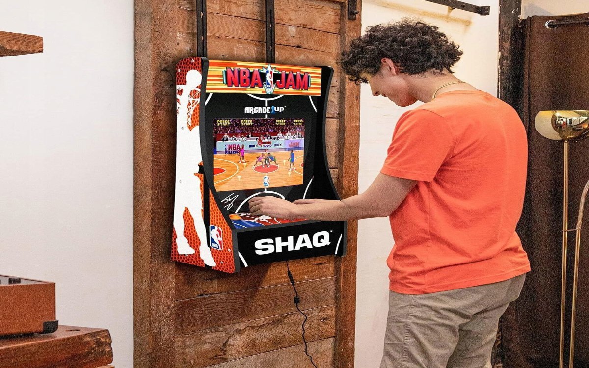 Osoba grająca na automacie ARCADE1UP który jest zamontowany na ścianie.