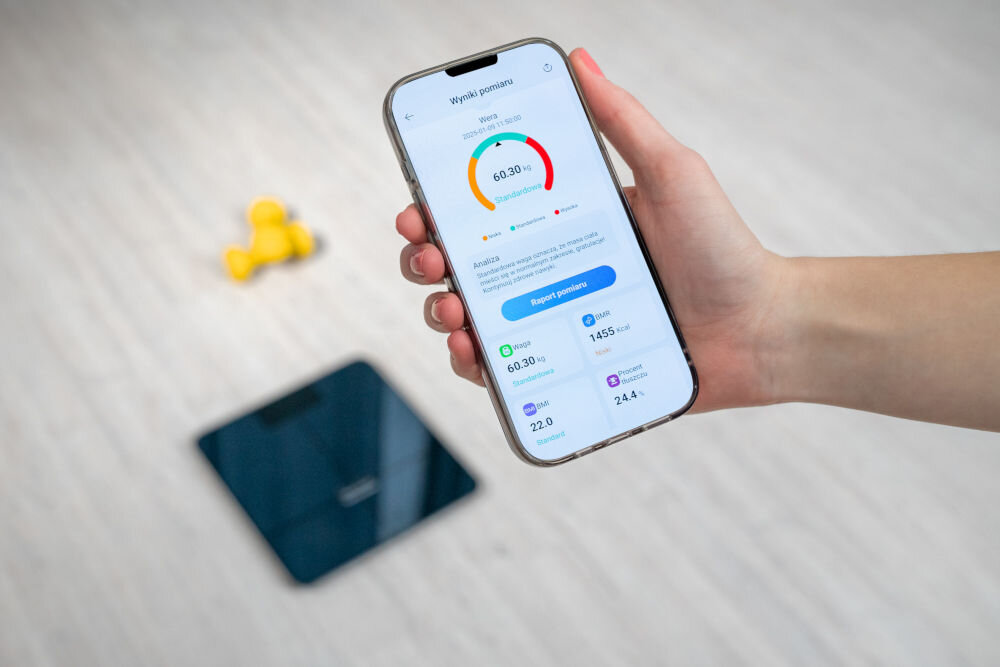 Waga łazienkowa GOTZE & JENSEN Analizator BT BS910K telefon z włączoną aplikacją mobilną trzymany w ręce bluetooth profile użytkowników aplikacja