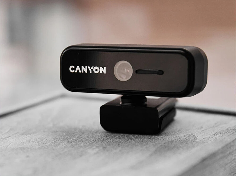 Kamera CANYON C2N USB-A - 1080p, przesłona kamery, prywatność, ochrona, bezpieczeństwo, Kamera internetowa stojąca na jasnym podłożu.