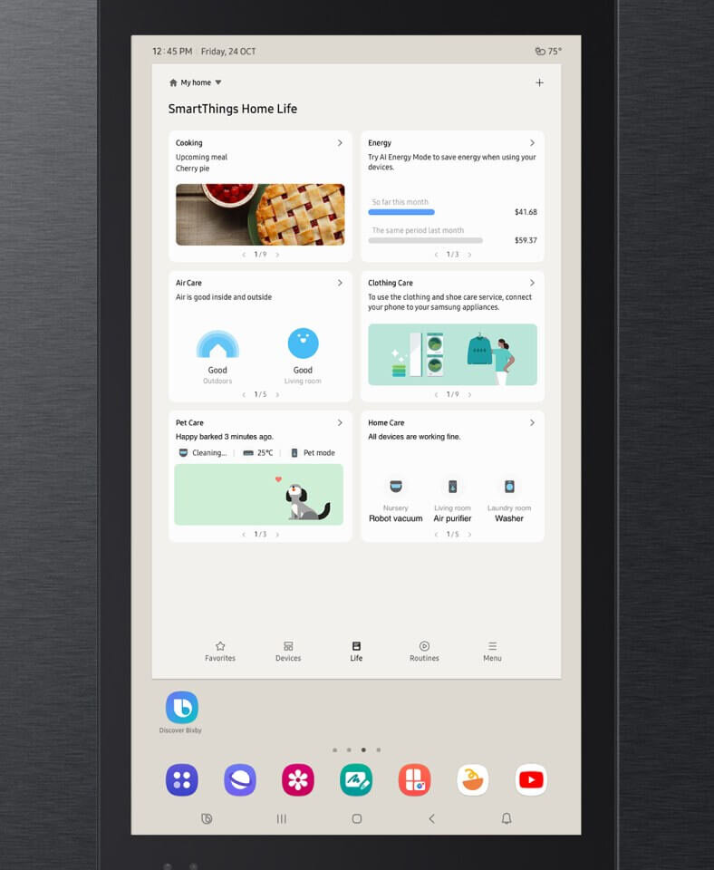 Ekran lodówki Samsung z aplikacją SmartThings Home Life, pokazujący różne sekcje takie jak Cooking, Energy, Air Care, Clothing Care, Pet Care i Home Care. Na dole ekranu widoczne są ikony aplikacji, w tym Discover Bixby, oraz godzina 12:45 PM i data Friday, 24 OCT.