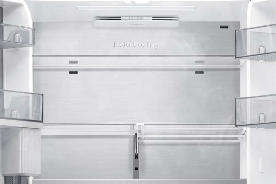 Wnętrze lodówki z widocznymi półkami i napisem \'Metal Cooling\' na tylnej ścianie. Widać również delikatną mgiełkę, sugerującą chłodzenie.