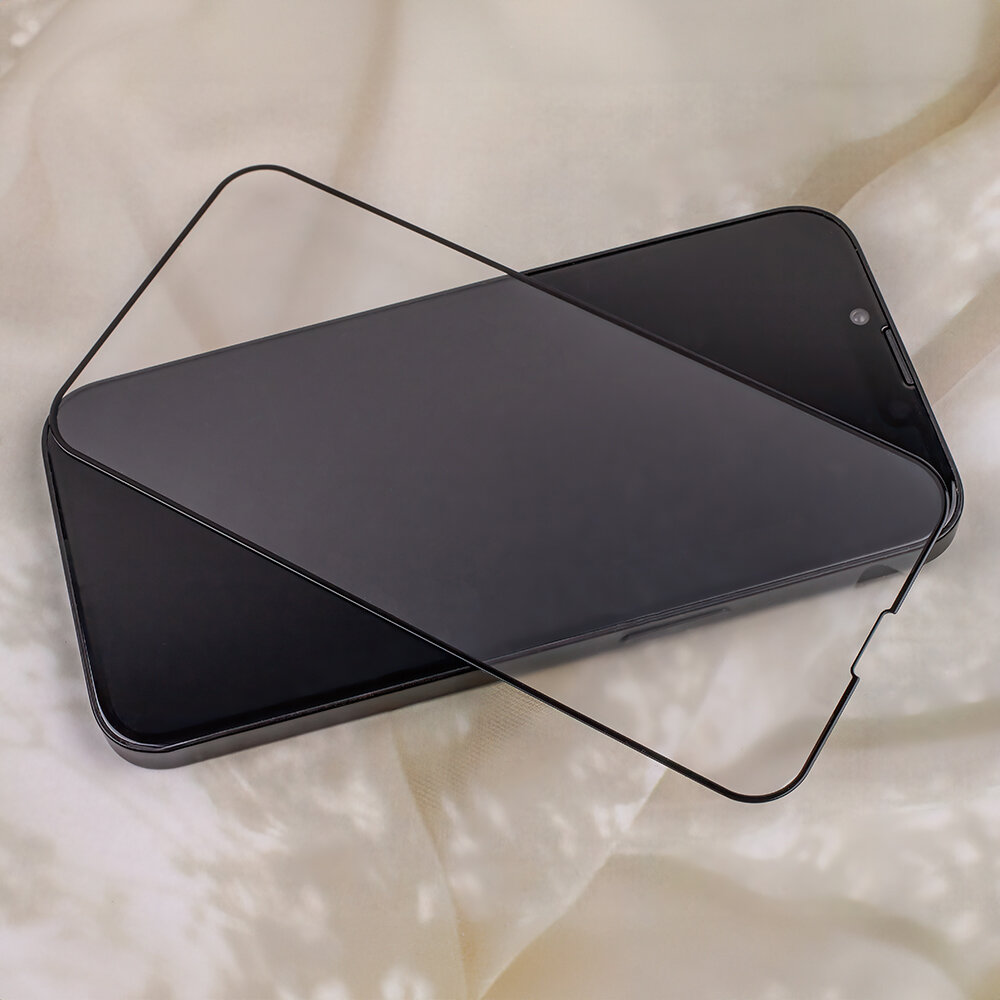 Na obrazie widać smartfon z nałożonym szkłem hartowanym, które jest matowe i dopasowane do ekranu. Tło jest jasne i nieostre.