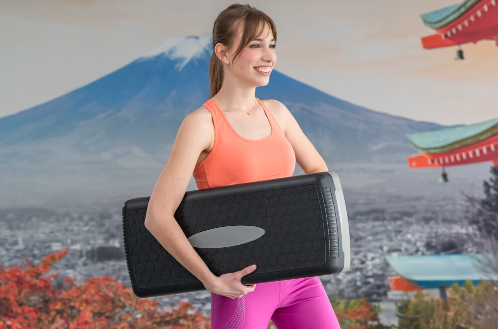 Step S_LINE SA022BG Czarno-szary sala gimnastyczna osoba trzyma step w dłoniach bezpieczny trening dynamika zdrowie ćwiczenia