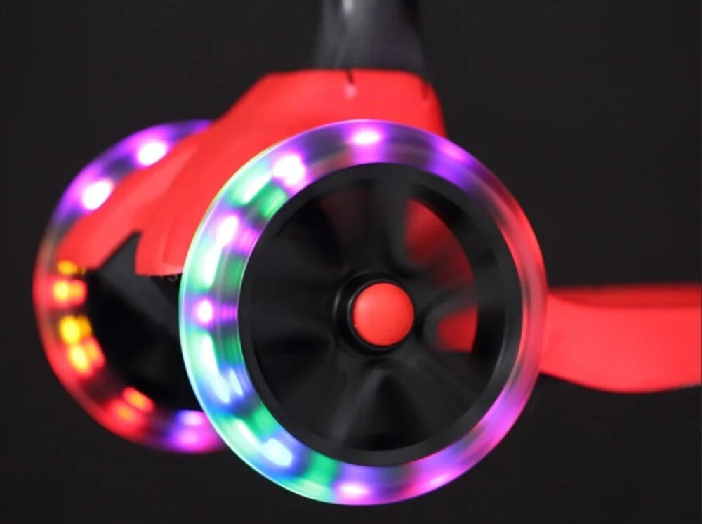 Hulajnoga dla dzieci EXTRALINK Baby Adventure ciemne tło zbliżenie na kółka kółka podświetlone na kolorowo podświetlane przednie kółka LED światełka LED wytwarzane są poprzez ruch