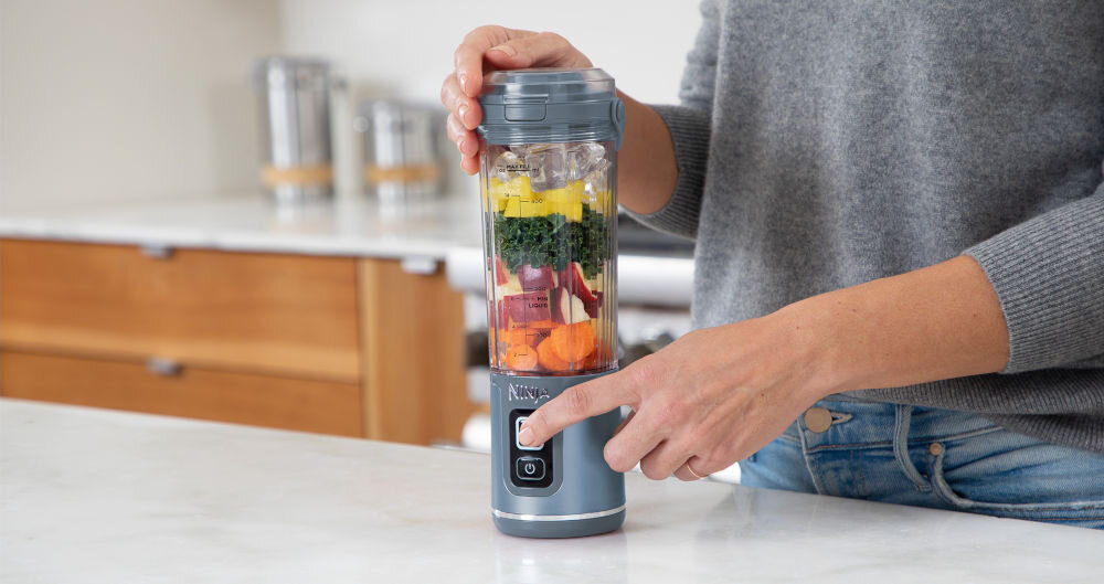 Blender personalny NINJA Blast BC151EUNV Niebieski Bezprzewodowy blender niebieska obudowa składniki wewnątrz pojemnika osoba naciska przycisk łatwość obsługi funkcja pulsowanie i blendowania jeden przycisk przykręcenie kielicha do podstawy załadować składniki założenie pokrywy włączenie urządzenia naciśnięcie przycisku START/STOP blendowanie przez 30 sekund po zakończeniu obrócenie blendera zdjęcie podstawki silnika