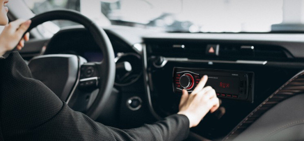 Radio samochodowe VORDON HT-175U London 1-DIN ekran LED czerwone podświetlenie, osoba siedząca za kierownicą obsługująca radio