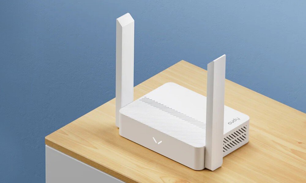 Router CUDY WR300 Urządzenie sieciowe w kolorze białym z dwiema pionowymi antenami, ustawione na drewnianym blacie przy niebieskiej ścianie, opis