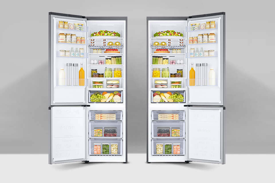 Obraz przedstawia dwie otwarte lodówki wypełnione różnorodnymi produktami spożywczymi, takimi jak owoce, warzywa, napoje i słoiki. Lodówki mają metaliczny grafitowy kolor i są wyposażone w półki oraz szuflady.
