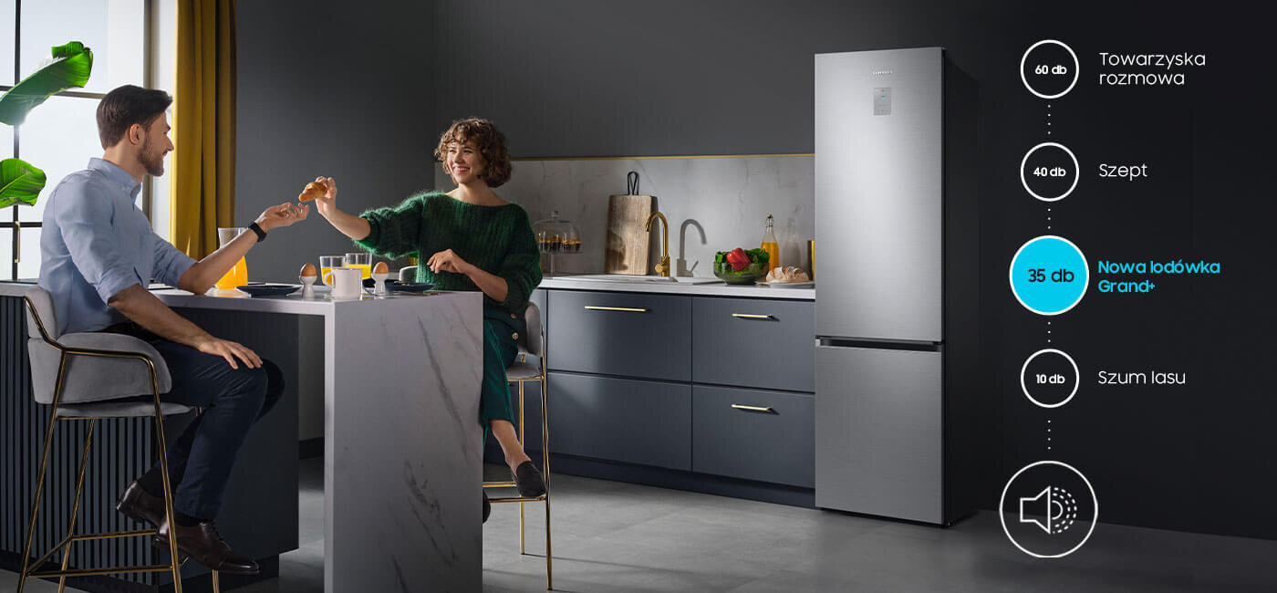 W kuchni przy stole siedzą dwie osoby, a obok znajduje się lodówka w kolorze szczotkowanej stali nierdzewnej. Na obrazie widoczny jest tekst: \'60 dB Towarzyska rozmowa\', \'40 dB Szept\', \'35 dB Nowa lodówka Grand+\', \'10 dB Szum lasu\'.