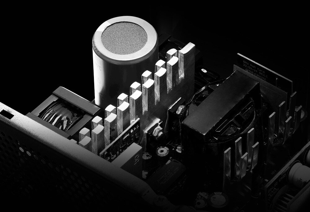 Zasilacz ADATA XPG Kyber Zbliżenie na wnętrze zasilacza, widoczny duży kondensator, radiator i elementy elektroniczne, w czarno-białym stylu, zabezpieczenia, ochrona