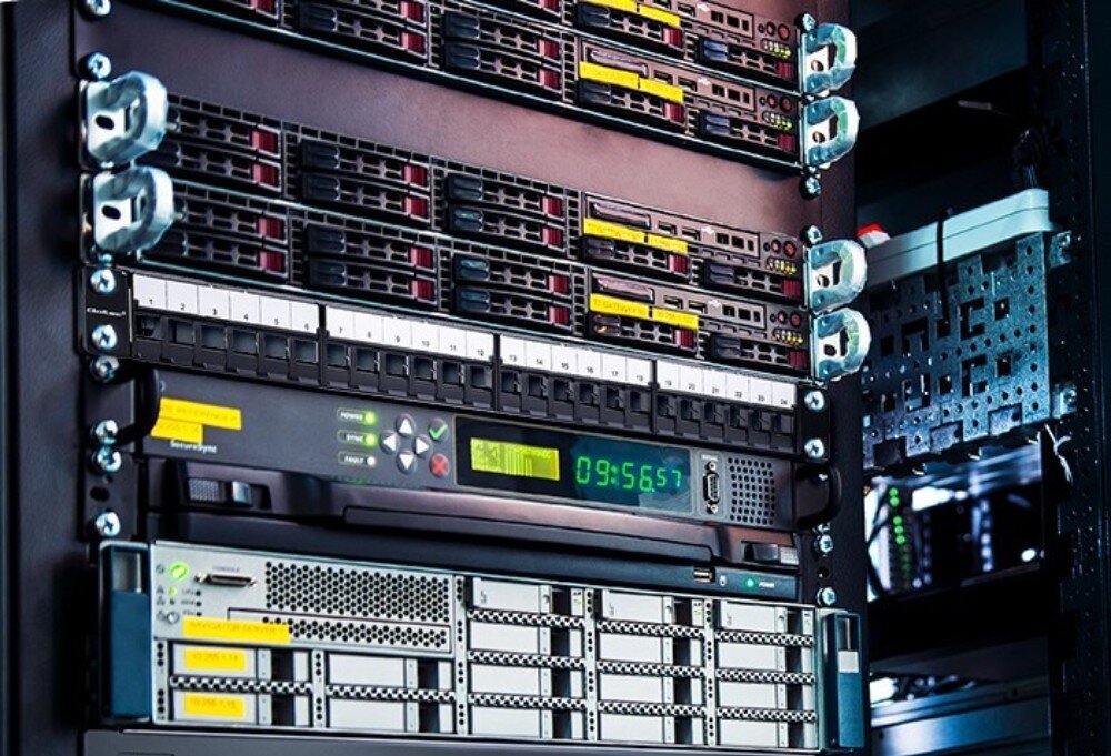 Patch panel QOLTEC 54516 Szafa serwerowa wypełniona sprzętem sieciowym i serwerowym, w centralnej części widoczny czarny panel z ponumerowanymi portami oraz podłączonymi urządzeniami z diodami LED, konstrukcja, wysokość, porty