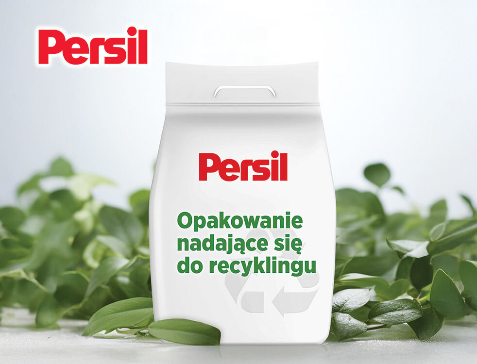 Proszek do prania PERSIL Ekologiczna reklama Persil. Opakowanie proszku do prania w formie torby na tle zielonych liści. Widoczny napis: Opakowanie nadające się do recyklingu z symbolem recyklingu.