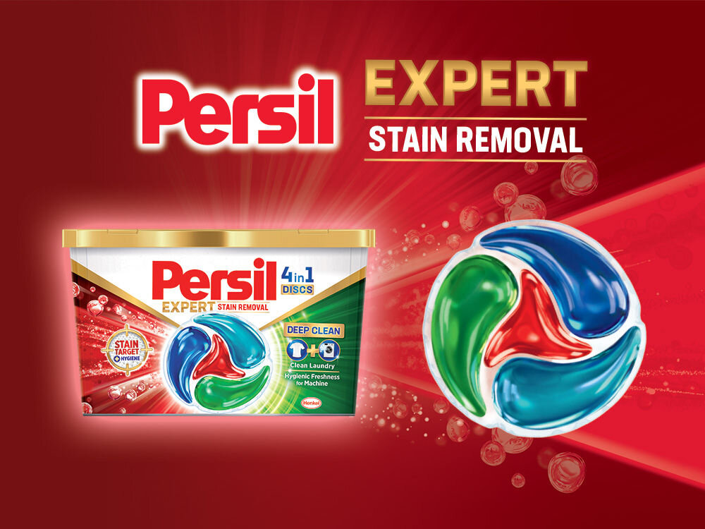 Kapsułki do prania PERSIL Reklama kapsułek Persil 4in1 Discs Expert Stain Removal. Duże opakowanie kapsułek na tle czerwonych promieni światła. Obok w powiększeniu widoczna jedna czerwono-zielono-niebieska kapsułka. Hasło główne: Persil Expert Stain Removal (Expert w usuwaniu plam).