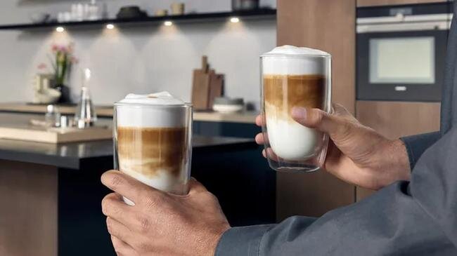 SIEMENS serii EQ900 Plus - dwie szklanki z kawą trzymane w rękach