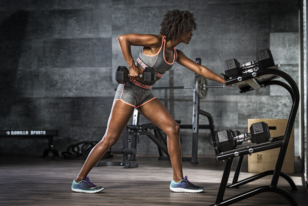 Hantla GORILLA SPORTS Hantla sześciokątna pełnym zakresem ruchu mniejsze i słabsze grupy mięśniowe 17,5 kg - kobieta ćwicząca z hantlami