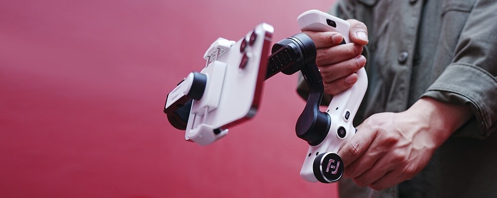 Mężczyzna w oliwkowej koszuli prezentuje na malinowym tle stabilizator FeiyuTech Scorp mini P Kit w kolorze białym.