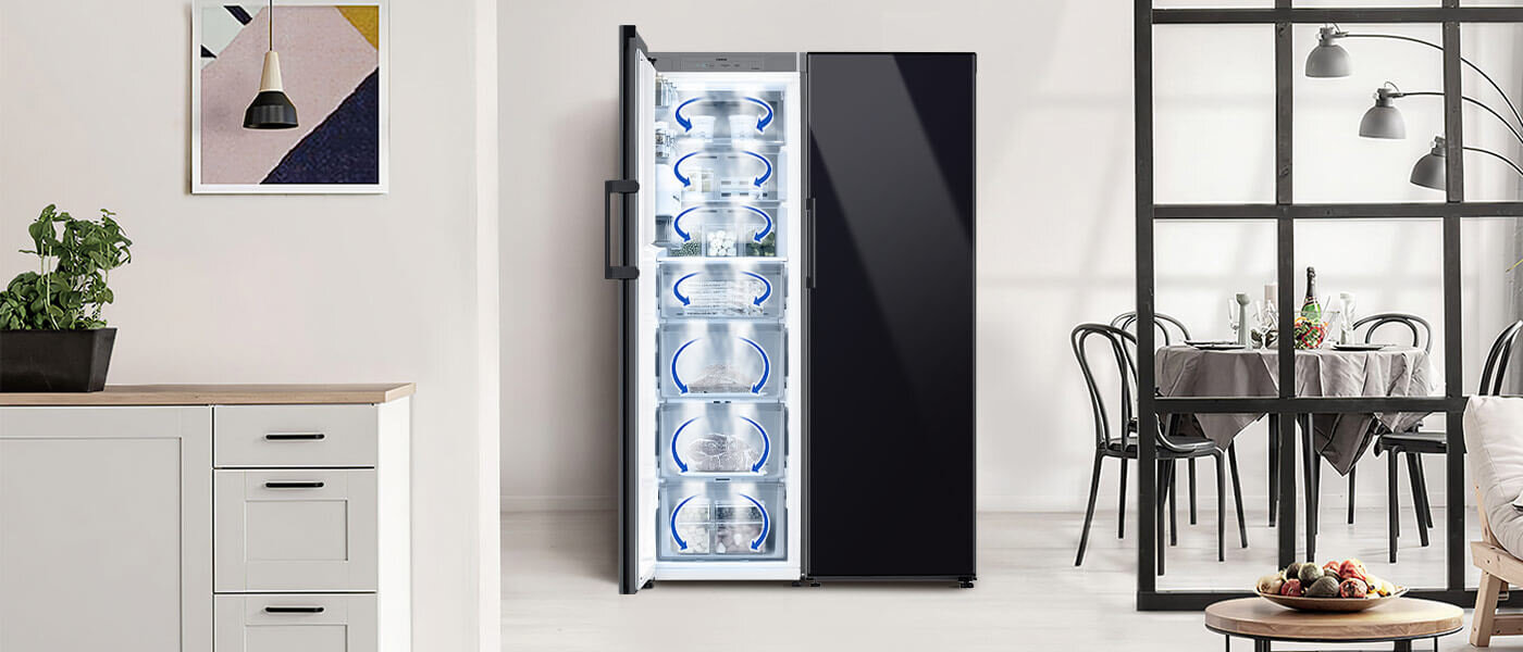Wizualizacja mrożenia w zamrażarce Samsung RZ32C76CE22, które zapewnione jest przez system All-Around Cooling Na obrazie widoczna jest otwarta zamrażarka z kilkoma przezroczystymi szufladami, umieszczona w nowoczesnym wnętrzu kuchennym. W tle znajduje się stół z krzesłami oraz dekoracje ścienne.