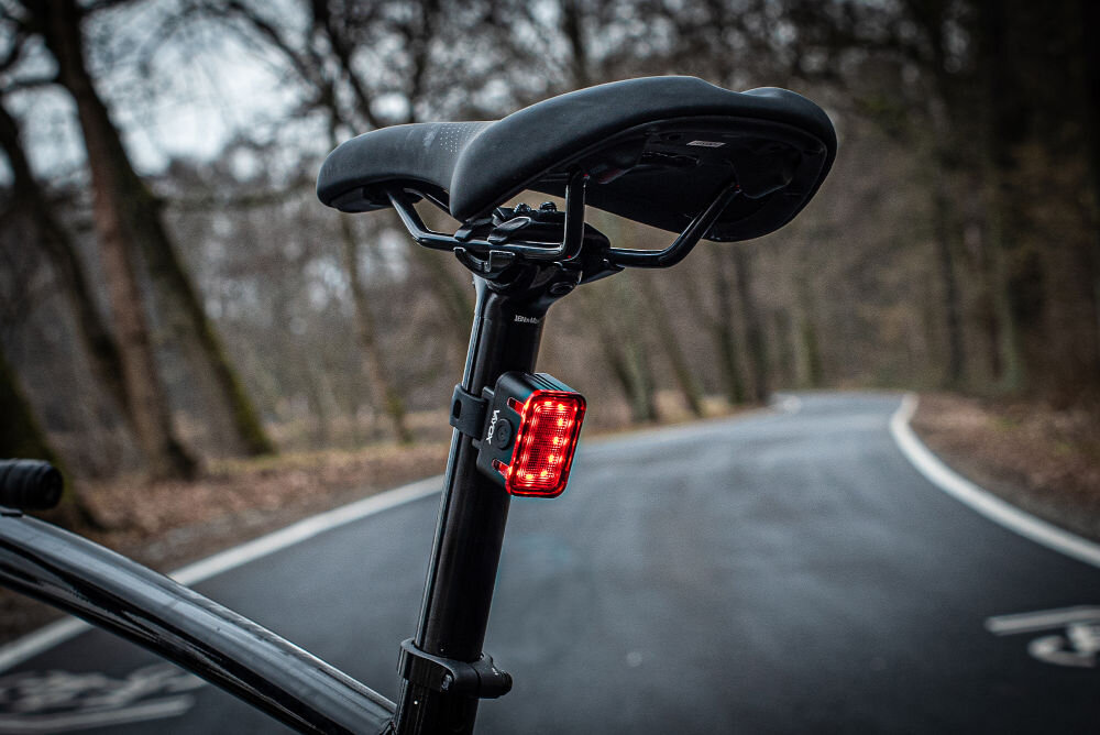 Lampka rowerowa VAYOX VA0152 na sztycy siodła w tle droga i las moc 300 lumnów 16 diod led