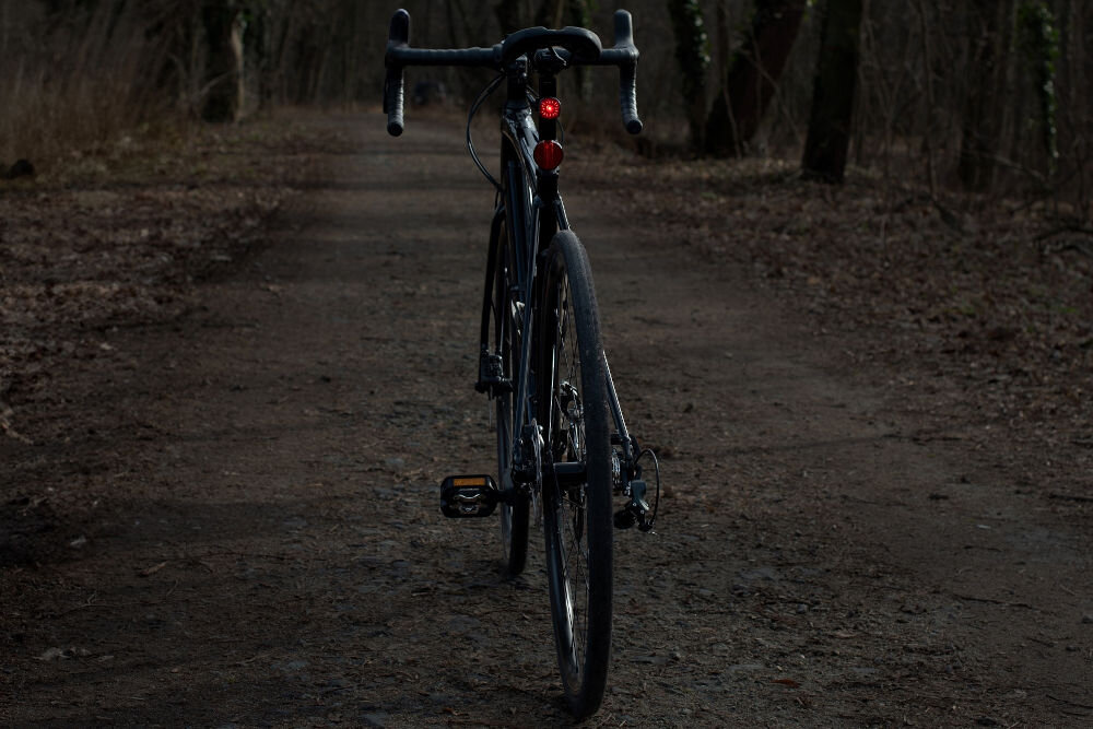 Lampka rowerowa VAYOX VA0156 zamontowana na rowerze widocznym w oddali 6 trybów zasięg światła czerwone diody led