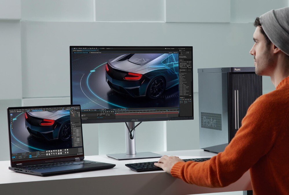 Monitor ASUS ProArt PA24ACRV Mężczyzna w czapce pracujący przy biurku. Przed nim stoi otwarty laptop, monitor oraz komputer stacjonarny z wyświetlanym projektem samochodu