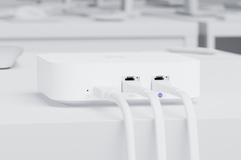 Router UBIQUITI UniFi Express (UX-EU) Zbliżenie na tylny panel białego routera z podłączonym kablem zasilającym i dwoma kablami sieciowymi
