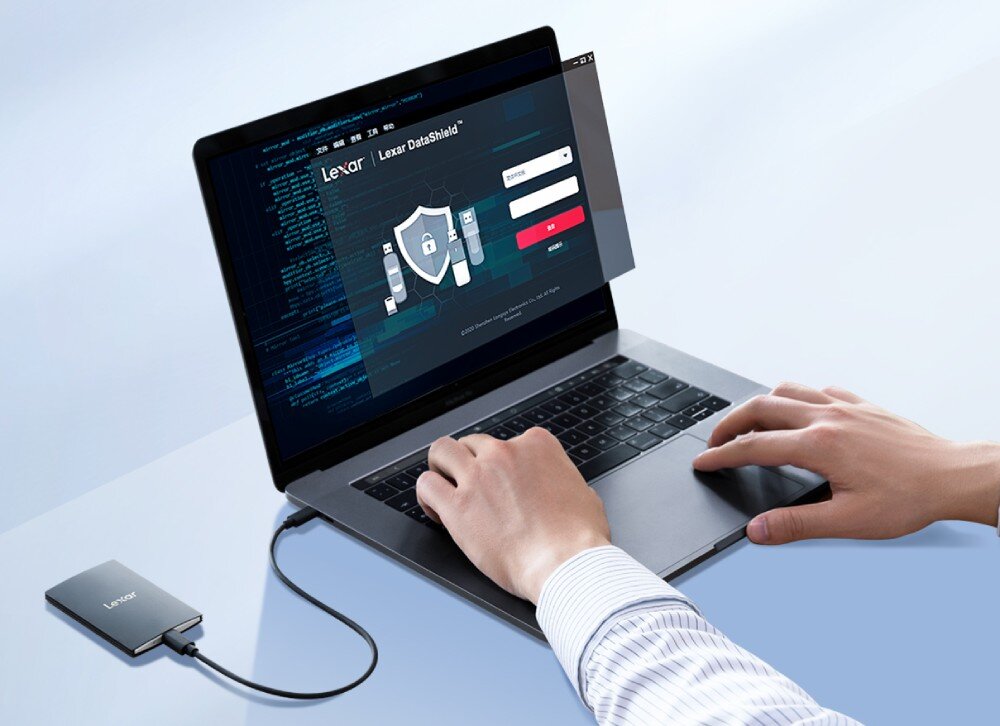 Dysk LEXAR SL500 Srebrny laptop wyświetlający aplikację 'Lexar DataShield' z ikoną tarczy na ekranie oraz podłączony do niego kablem czarny dysk zewnętrzny
