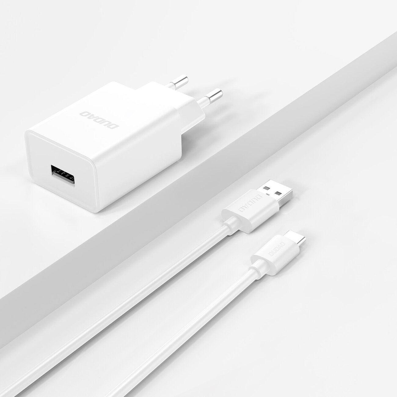 Na obrazie widoczna jest biała ładowarka sieciowa z logo \'DUDAO\' oraz biały kabel USB-A do USB-C z tym samym logo na wtyczkach.