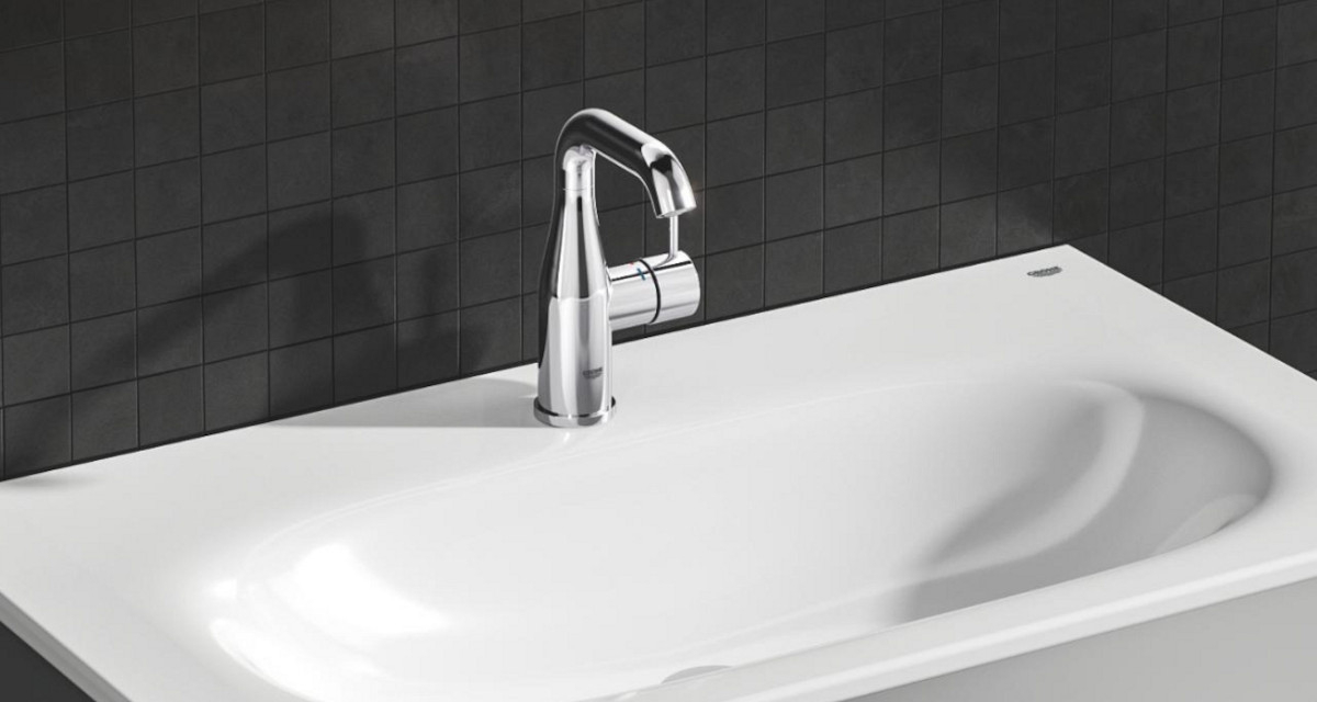 BATERIA UMYWALKOWA GROHE ESSENCE ROZMIAR M 23462001 CHROM Na zdjęciu znajduje się elegancka, chromowana bateria umywalkowa osadzona na białej, gładkiej umywalce o delikatnie profilowanym kształcie. Tło stanowi ciemna ściana z kwadratowych płytek, która podkreśla minimalistyczny charakter aranżacji elegancki design chrom Long-Life lustrzany blask odporność uszkodzenia łatwe czyszczenie stylowe wzornictwo