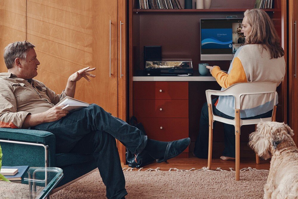 Komputer HP EliteOne 870 G9 Kobieta siedzi przy komputerze w zabudowanej wnęce biurowej, obok niej mężczyzna na fotelu i pies na dywanie, wyświetlacz, rozdzielczość, matryca