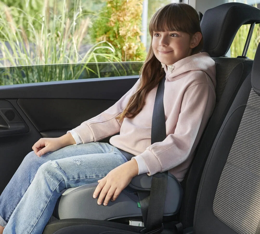 Podstawka samochodowa KINDERKRAFT I-Boost I-Size Szary wnętrze samochodu dziecku siedzi na podstawce przypięte pasami widok lekko z boku bezpieczeństwo wygoda ochrona