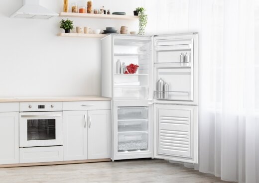 Lodówka MPM-215-KB-38/E z otwartymi drzwiami w zabudowie kuchennej. W lodówce butelki i owoce.