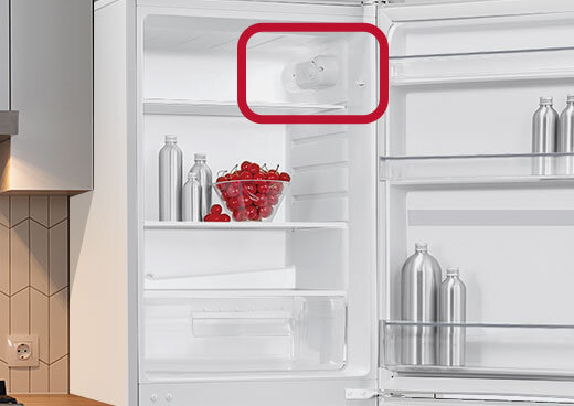 Zbliżenie na lodówkę MPM-215-KB-38/E z otwartymi drzwiami. Termostat zaznaczony czerwonym obramowaniem.