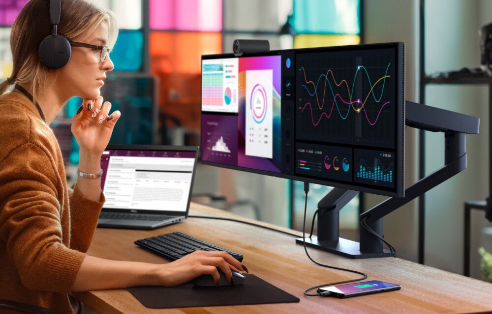 Monitor DELL P2425HE 23.8 1920×1080px IPS 100Hz (bez podstawy) osoba siedząca przy stanowisku korzystająca z laptopa, do którego podłączony jest monitor opis