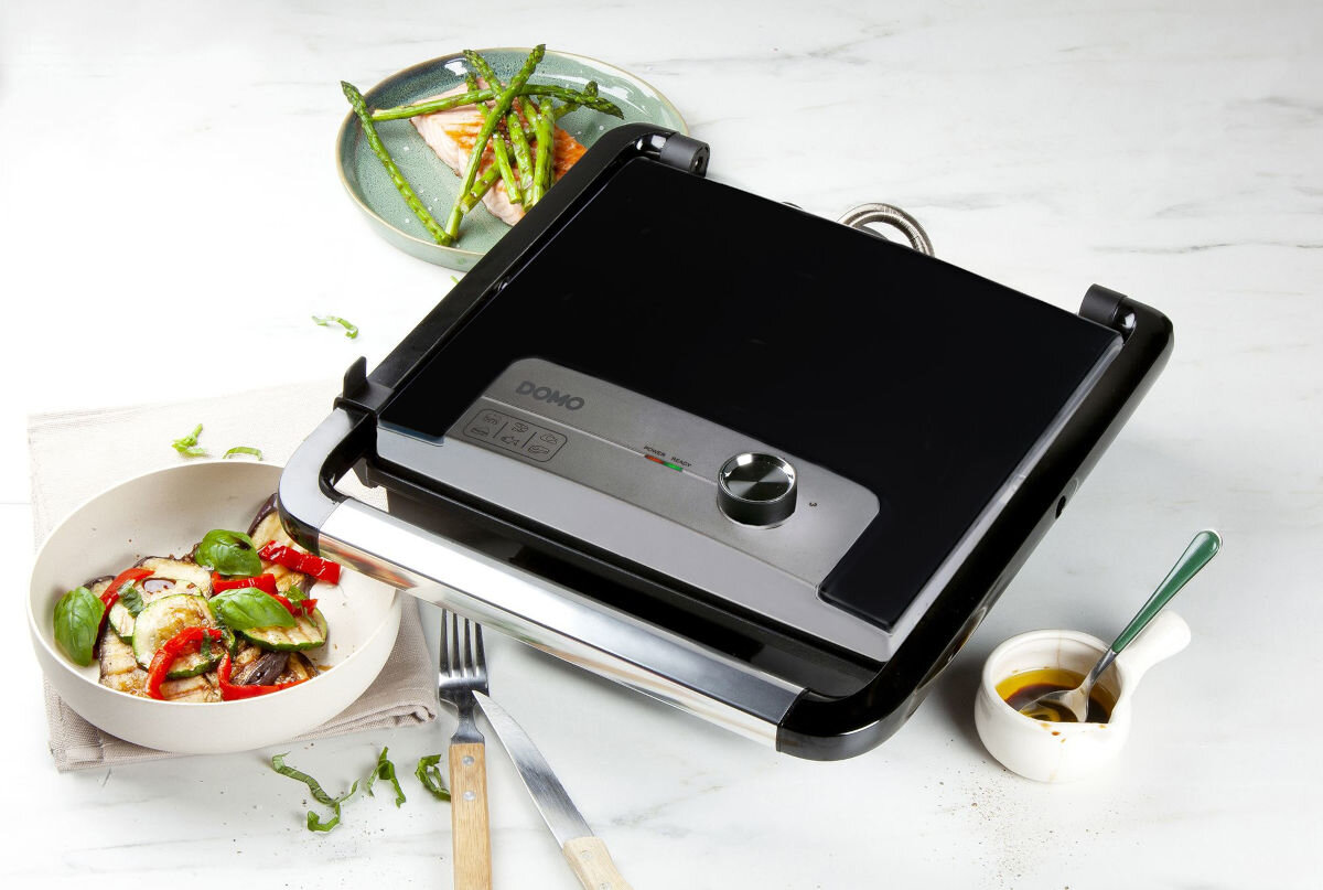 Grill elektryczny DOMO DO9245G, grill kontaktowy, duża powierzchnia, pływająca pokrywa, domowe grillowanie, Zamknięty grill Domo DO9245G, panel sterowania z pokrętłem i ikonami, danie z grillowanych warzyw i łosoś na talerzu obok