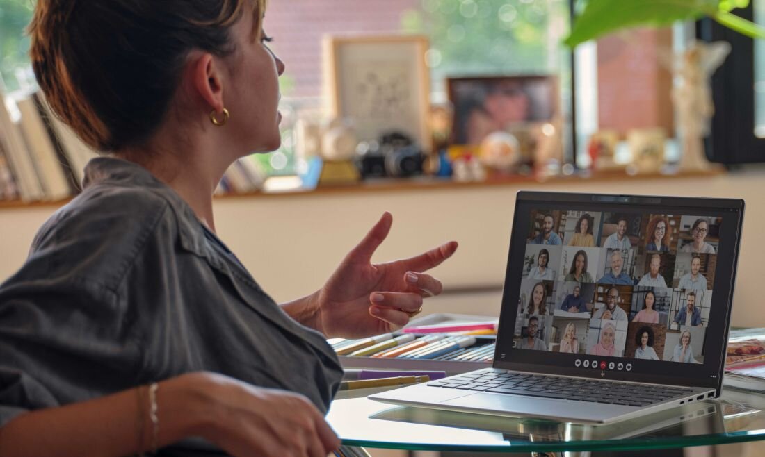 Laptop HP Pavilion 15 - Kobieta siedzi przy stole z laptopem HP Pavilion 15, rozmawiając z grupą ludzi na ekranie.