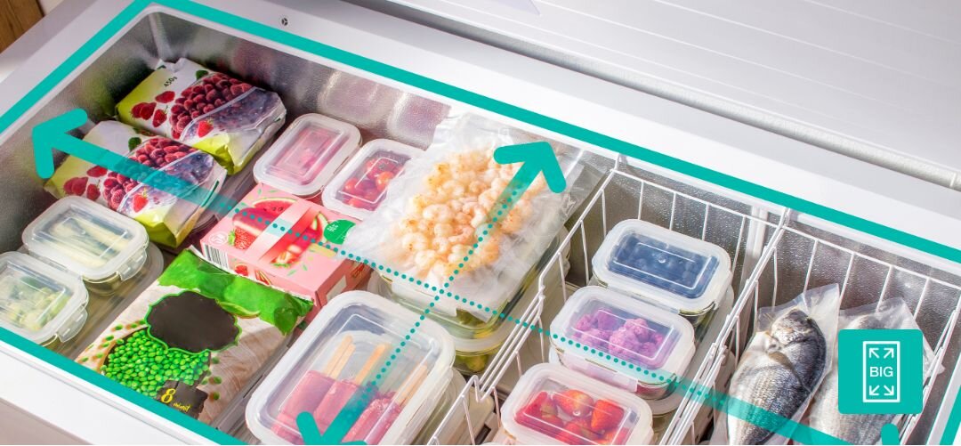 ZAMRAŻARKA GORENJE FHC42EAW Wnętrze pojemnej zamrażarki skrzyniowej z ułożonymi opakowaniami mrożonek, pojemnikami i rybą, nad którymi poprowadzono turkusowe strzałki wskazujące dużą przestrzeń przechowywania zamrażarka skrzyniowa duża pojemność przechowywanie mrożonek dużo miejsca na żywność