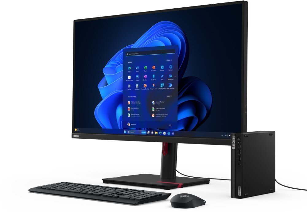 Komputer LENOVO ThinkCentre M70q Gen 5 Czarny komputer w małej obudowie stojący pionowo obok monitora z wyświetlonym systemem operacyjnym, klawiatury oraz myszy na białym tle, obudowa, wielkość, procesor, rdzenie