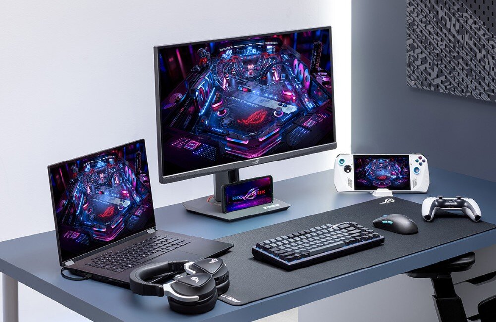 Monitor ASUS ROG Strix XG259QNS Biurko z monitorem, laptopem, kontrolerem, słuchawkami i konsolą przenośną. Na ekranach tych urządzeń widoczna ta sama gra w stylu cyberpunkowym, miejsce na telefon, gniazdo statywowe