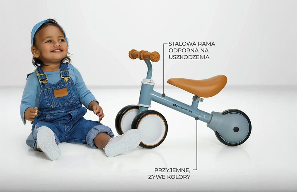 Kinderkraft rowerek biegowy CUTIE LIGHT BEIGE białe tło dziecko siedzi obok niebieskiego rowerka strzałki kółka siodełko funkcjonalność estetyka 50 x 22 x 37 cm lekka konstrukcja o wadze 1,8 kg poręczny wygodny w użytkowaniu rozwój równowagi koordynacji bezpieczna budowa pastelowa kolorystyka Solidne wykonanie (metalowa rama) trwałość przemyślane rozwiązania codzienne spacery i zabawy