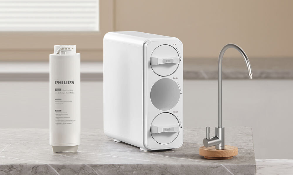 Wkład filtrujący PHILIPS AUT820/10 Wkład filtrujący PHILIPS Ion Exchange Resin obok stacji filtracji wody i kranu na blacie kuchennym.