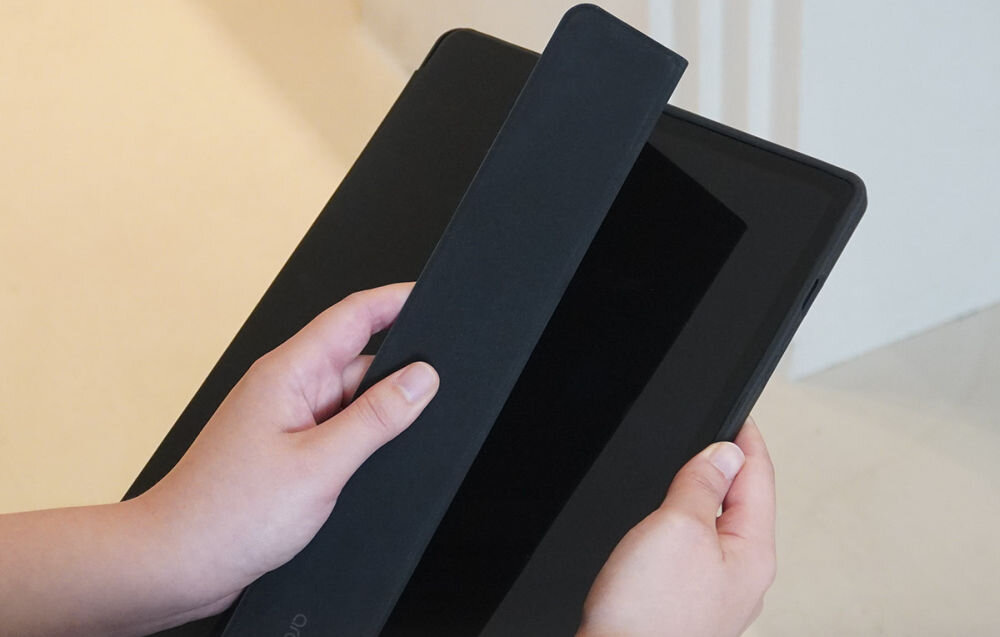 Etui Araree A Folio Sam Tab A9 Plus funkcja stojaka regulowane kąty oglądania i pracy etui do tabletu Dłonie zdejmujące lub nakładające magnetyczną, podłużną klapkę zabezpieczającą rysik na pleckach czarnego etui tabletu.