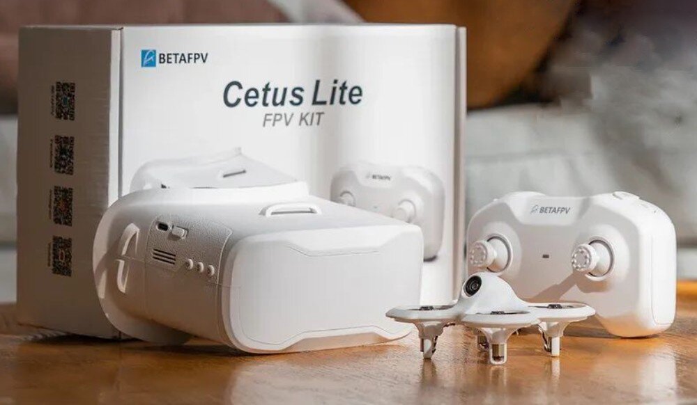 Dron BETAFPV Cetus Lite FPV Kit Kompletny zestaw FPV z białym dronem, gogle i kontroler ułożone przed pudełkiem produktu na stole