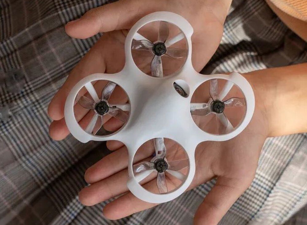 Dron BETAFPV Cetus Lite FPV Kit Widok od spodu drona trzymanego w dłoni, pokazujący osłony śmigieł i cztery silniki w białej ramie